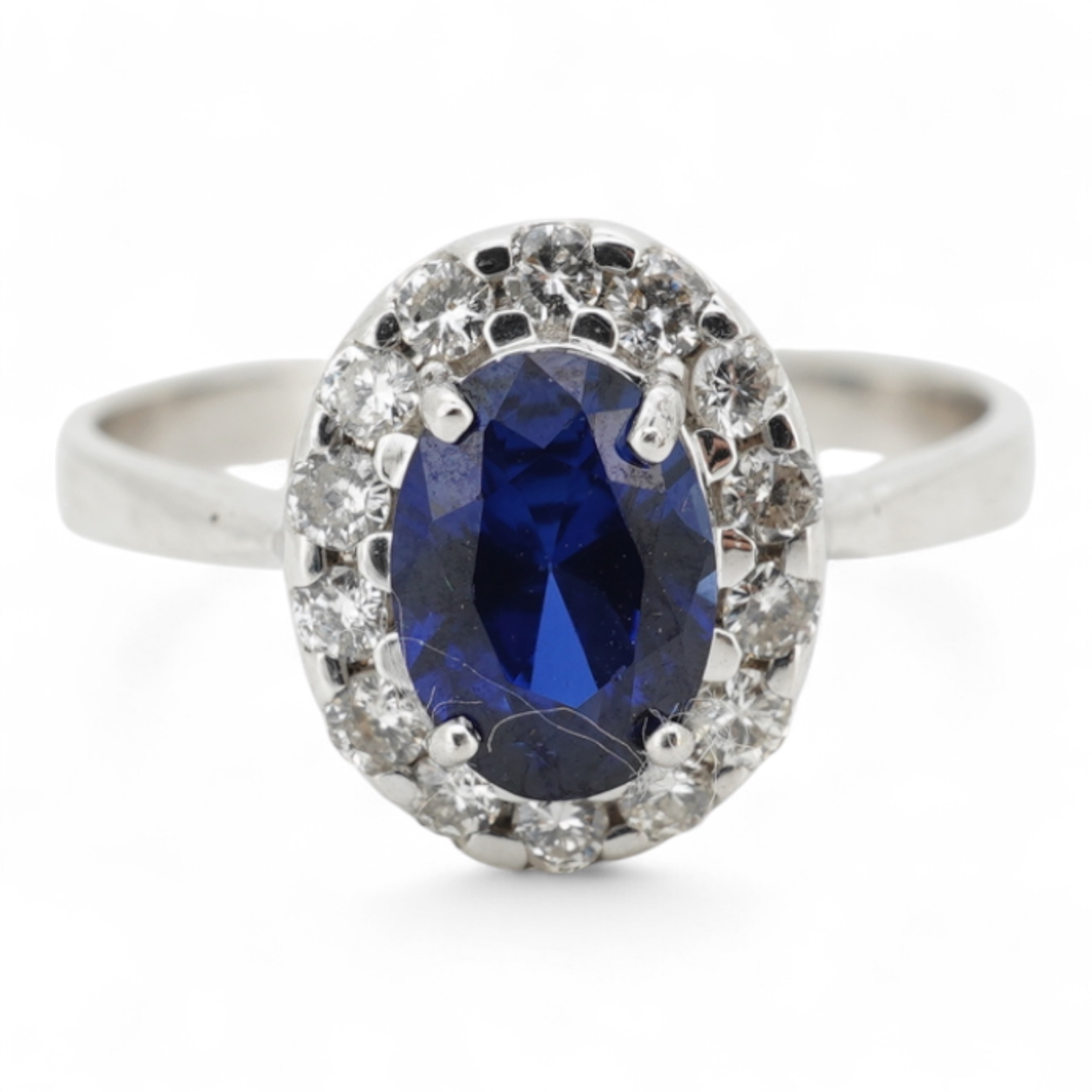 A synthetic sapphire and diamond cluster ring, mounted in white gold, size L1/2, stamped 18K, gross weight approximately 1.5 grams